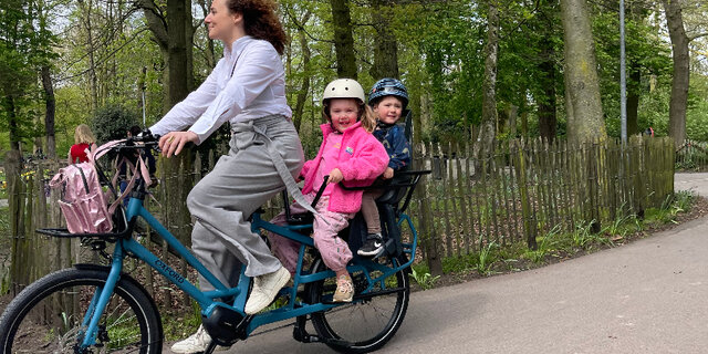 Een vrouw met kind op een longtail fiets